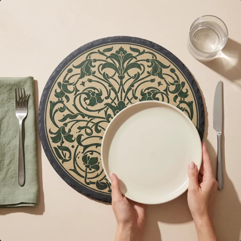 Hands setting a dinner plate onto a Heirloom Manor slate placemat